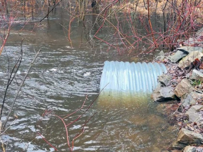 A galvanized steel culvert inundated with flood waters.