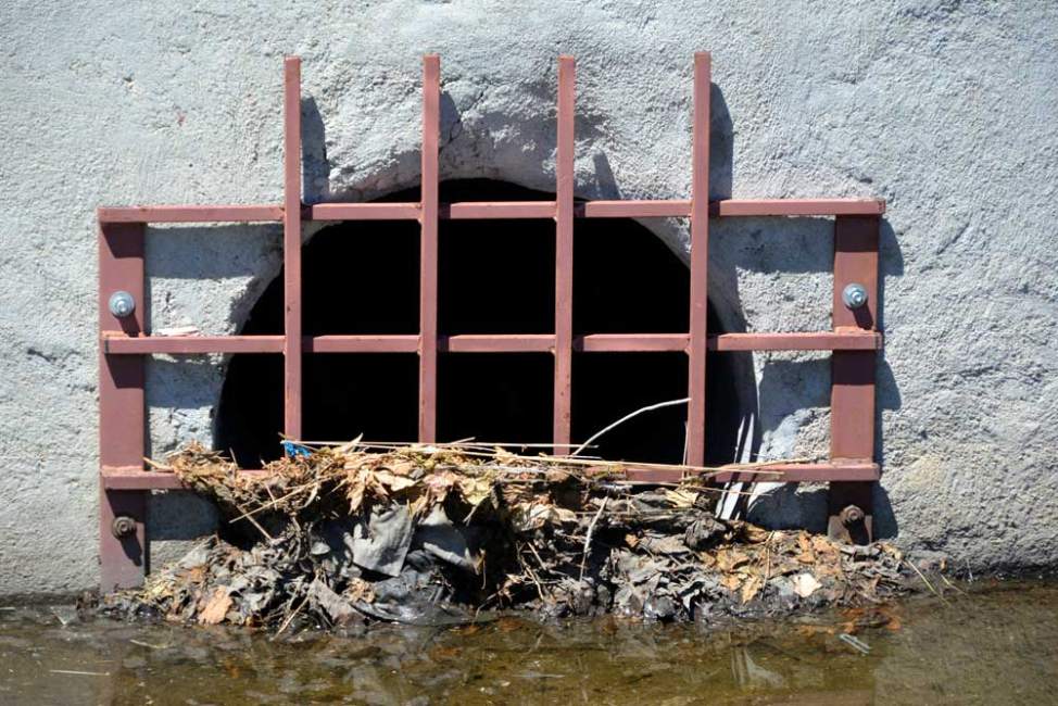 Concrete headwall and debris grate on culvert inlet.