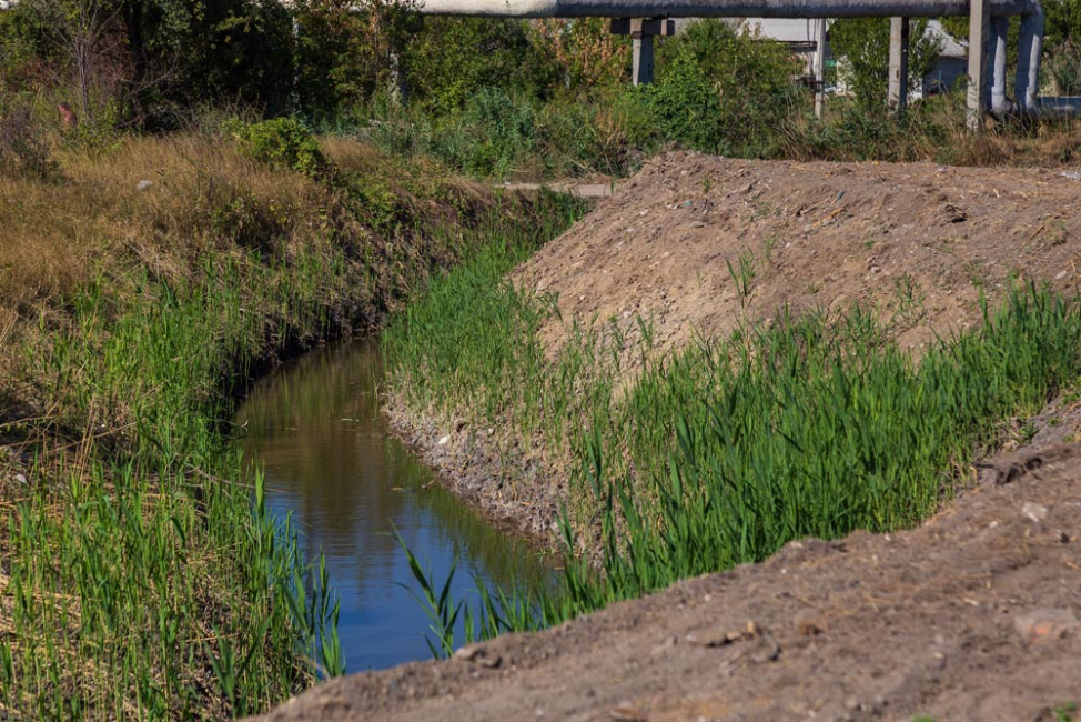 Drainage channel with steep sloped earthen banks.