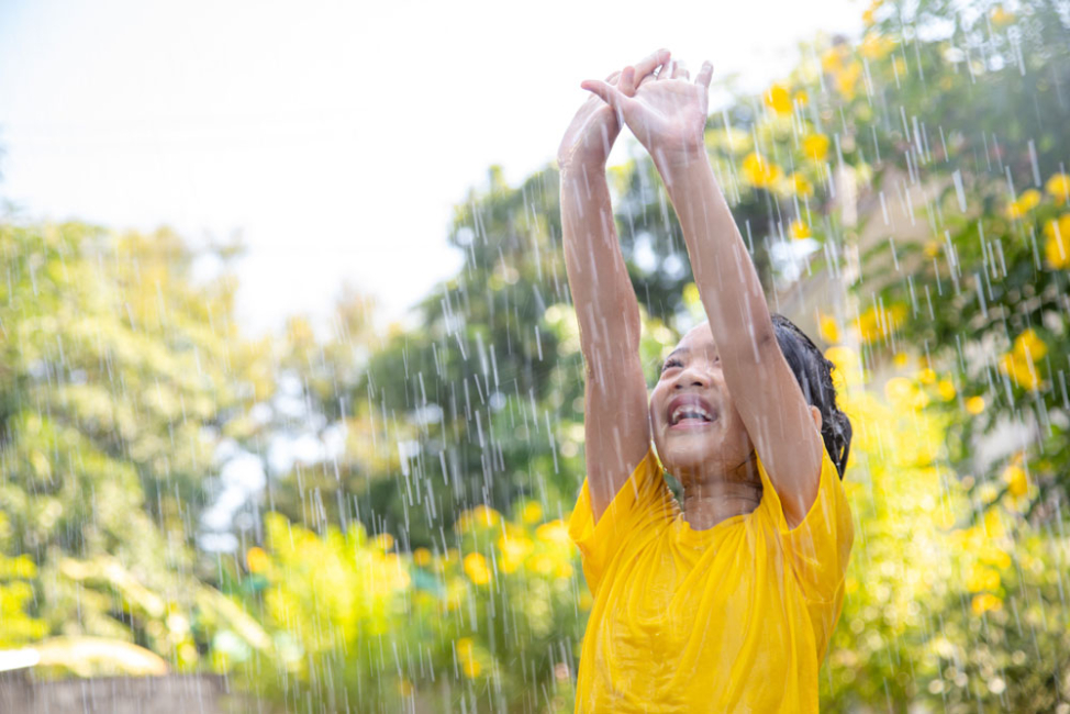 Young girl playing outside in the rain.