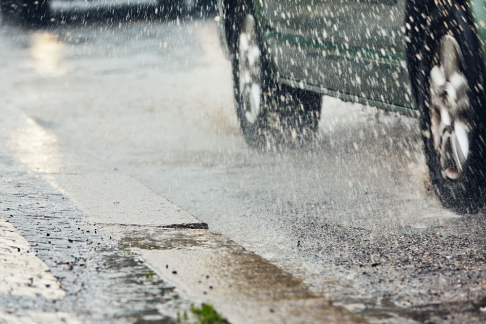 Car passes during heavy rain in city.
