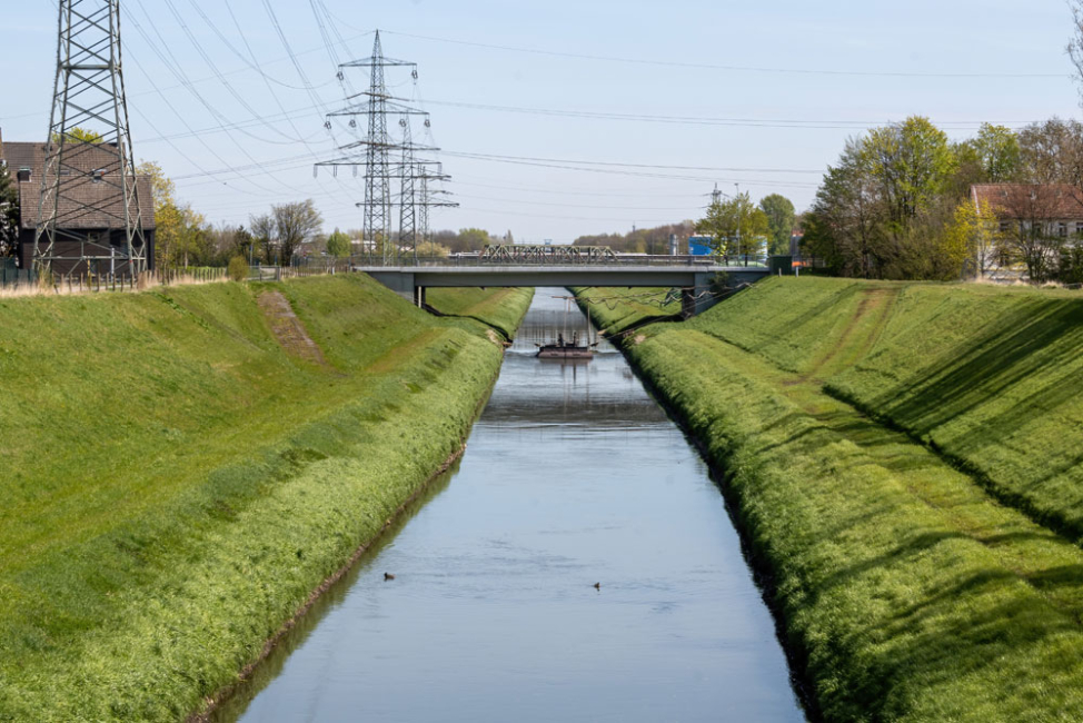 Large water-filled channel with grass-covered-banks.