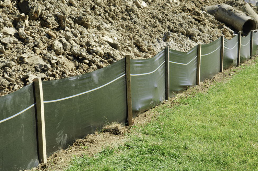 Silt fence installed at base of excavated soil on construction site.