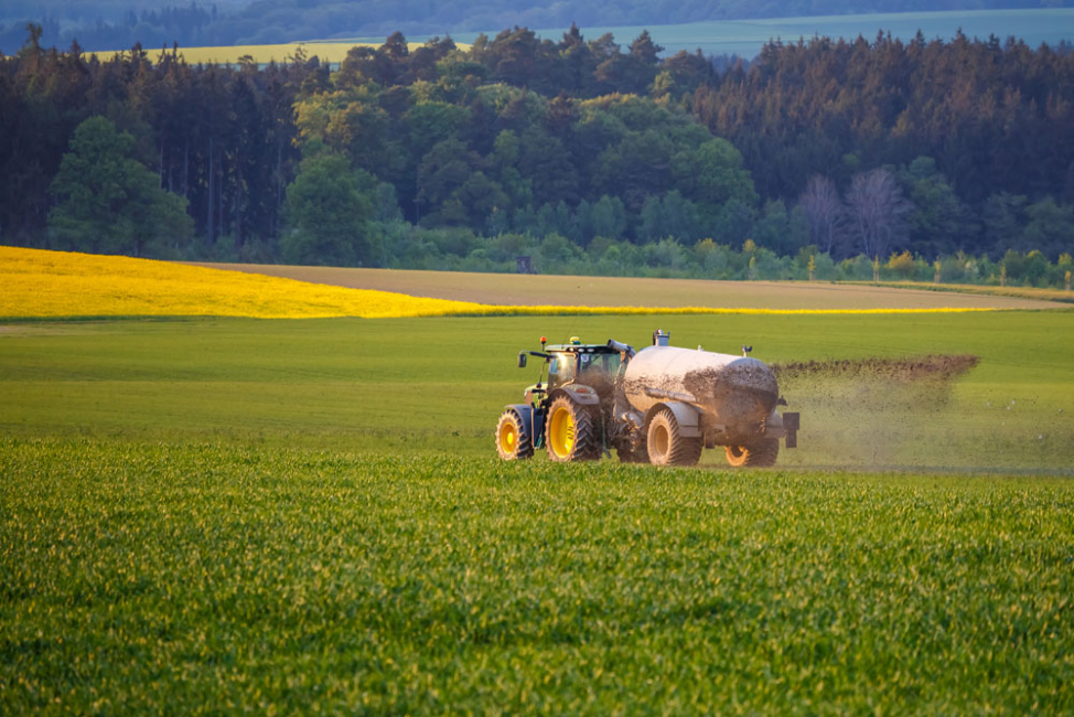 Farm tractor spraying liquified manure fertilizer on field.